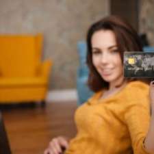 young woman with laptop showing credit card